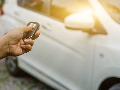 Hand using a smart key remote to unlock a car